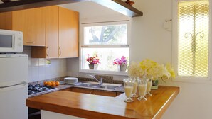 Une cuisine avec des meubles en bois, un four à micro-ondes, un évier et une fenêtre ornée de fleurs.