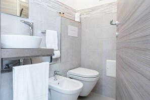 A modern bathroom with a sink, bidet, and toilet.