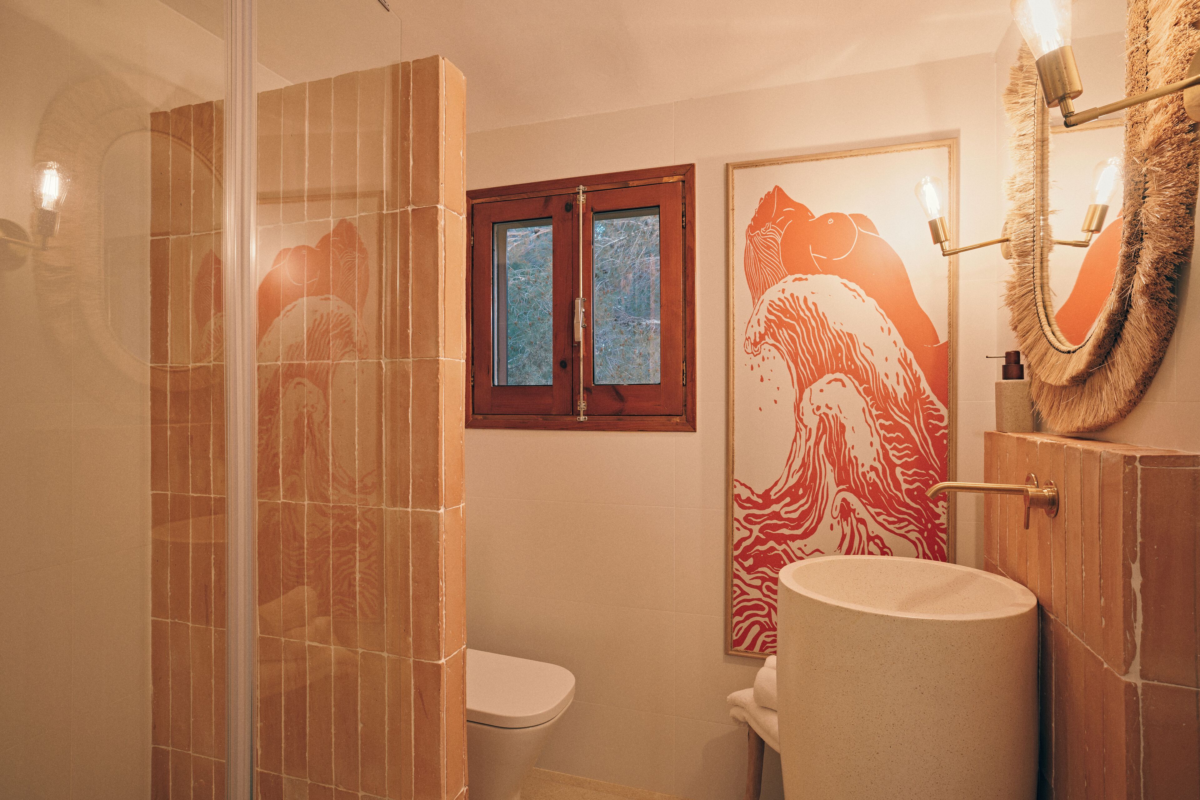 Een badkamer met een douchecabine van glas, een wit toilet en een wastafel met een spiegel erboven.