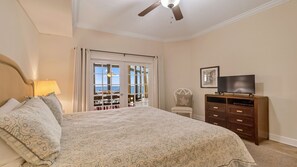 A bedroom with a large bed, a ceiling fan, a TV, a dresser, and a balcony with outdoor furniture. - New to the Rental Market - Lazy River and Slide! (Orange Beach)