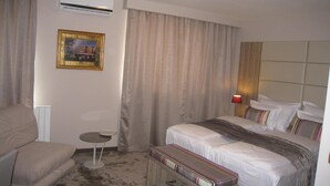 A hotel room with a bed, a chair, a small table, and an air conditioning unit on the wall. - VIP Hotel Sarajevo (Sarajevo)