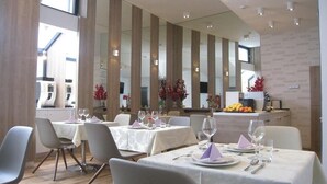 A restaurant with tables set for dining, featuring a modern interior with vertical wooden panels and a view of the cityscape. - VIP Hotel Sarajevo (Sarajevo)