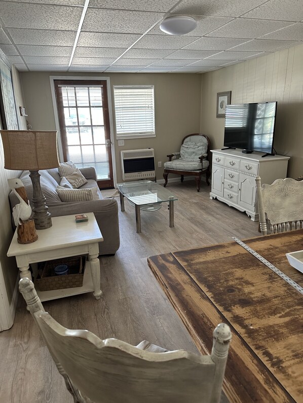 A living room with a sofa, armchair, coffee table, and a TV on a cabinet.