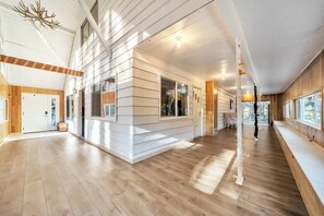 Spacious interior with a high ceiling and open-plan layout, featuring a bench and large window.