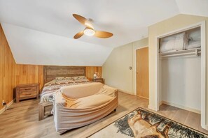 A bedroom with a bed, a wooden headboard, a ceiling fan, a nightstand, a bedside table, a wardrobe, and a patterned rug. - Luxe Private Mountainside Getaway in Pioneer! (Pioneer)