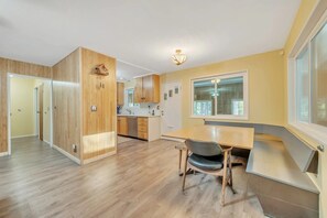 A modern kitchen with wooden cabinets, a dining table with chairs, and a large window providing natural light. - Luxe Private Mountainside Getaway in Pioneer! (Pioneer)