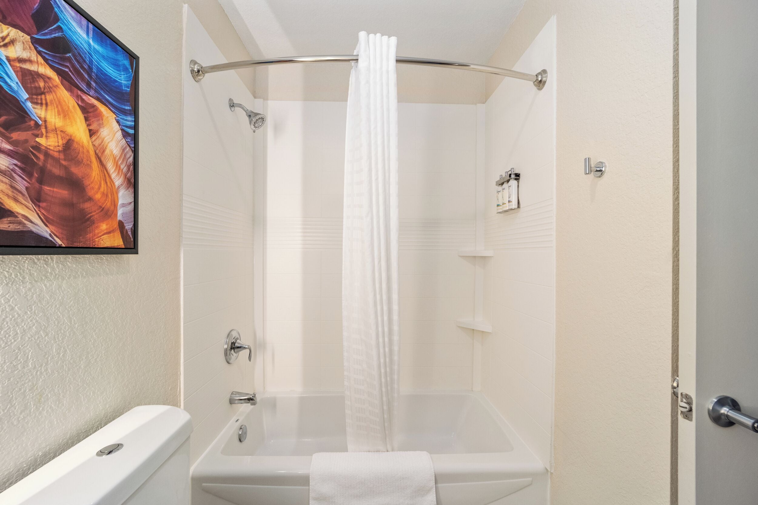 A bathroom with a bathtub, shower curtain, and a towel.