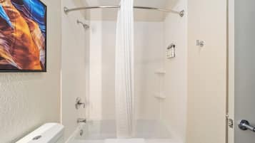 A bathroom with a bathtub, shower curtain, and a towel.