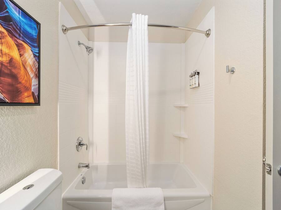 A bathroom with a bathtub, shower curtain, and a towel.