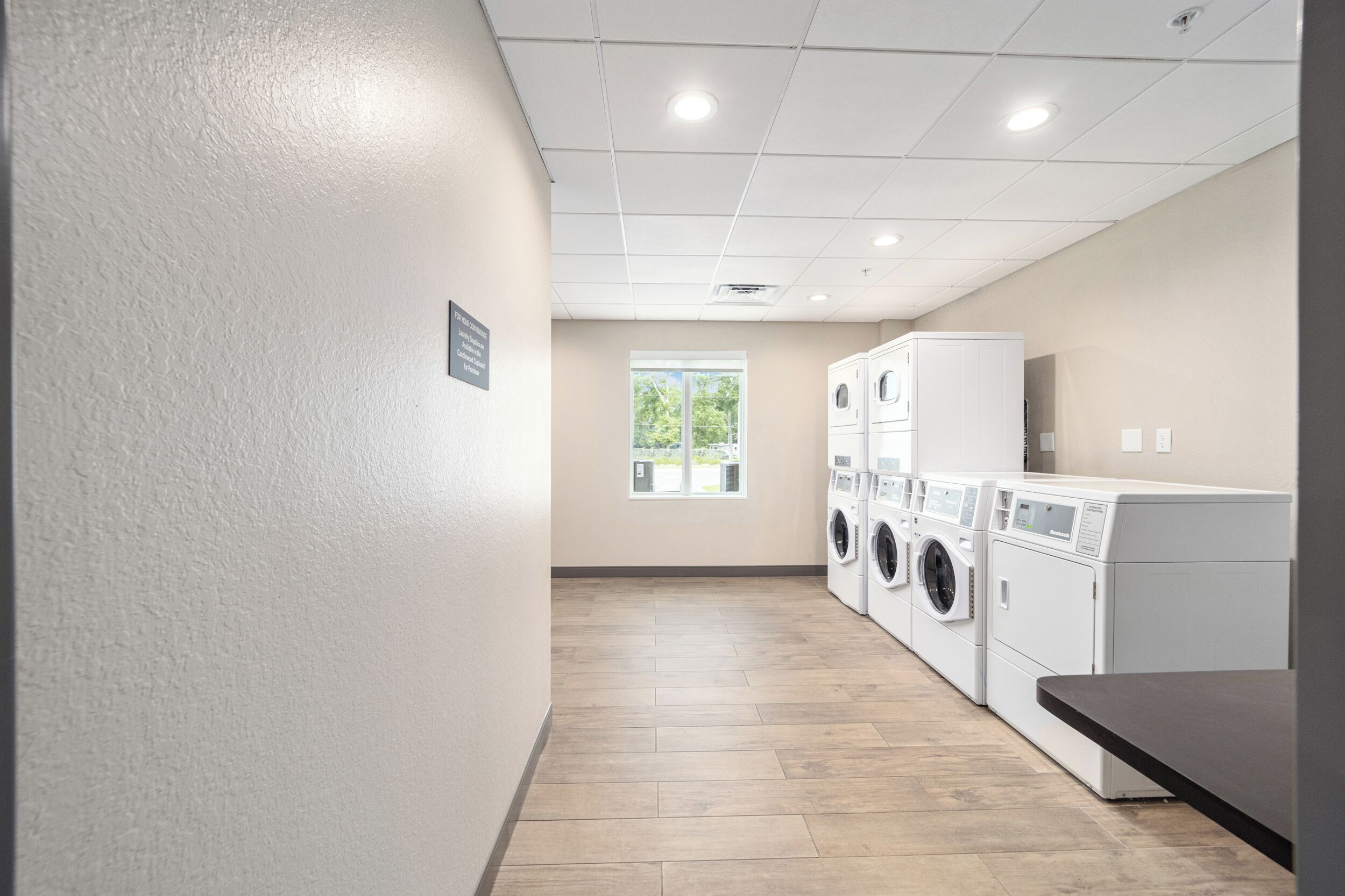 A laundry room with a tiled floor, a window, and stacked laundry machines.