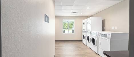 A laundry room with a tiled floor, a window, and stacked laundry machines.