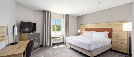 Una habitación de hotel con cama, escritorio, silla, televisión y vistas al exterior.