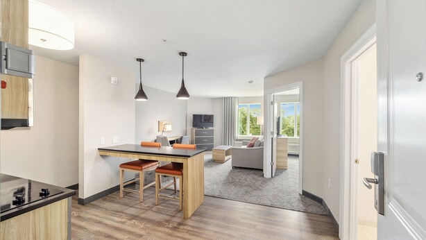 Una cocina moderna con una isla central, iluminación colgante y vistas a un balcón.