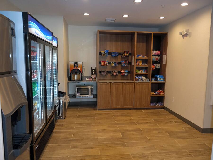 A kitchenette with a refrigerator, microwave, and coffee machine.