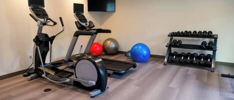 A gym with treadmills, exercise balls, and a rack of dumbbells.