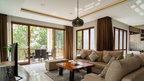 A modern living room with a sofa, coffee table, and a TV on a stand. - Anindya Hill Villa 7 Br Heated Pool and a Billiard (Bandung)