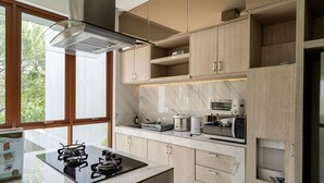 A modern kitchen with a gas stove, microwave, and built-in oven. - Anindya Hill Villa 7 Br Heated Pool and a Billiard (Bandung)