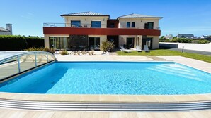Una casa moderna de dos pisos con una piscina al frente.