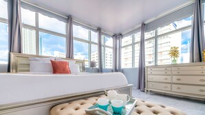 Una habitación de hotel con una cama grande, un aparador y una ventana con vistas a la ciudad.