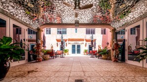 Un patio interior con suelo estampado, plantas en macetas y una estatua.