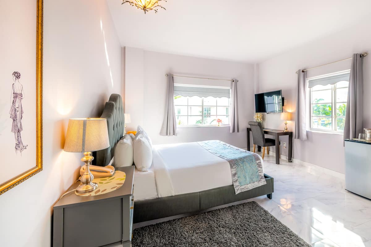 Een moderne hotelkamer met een groot bed, een bureau, een televisie en een raam met uitzicht op groen.
