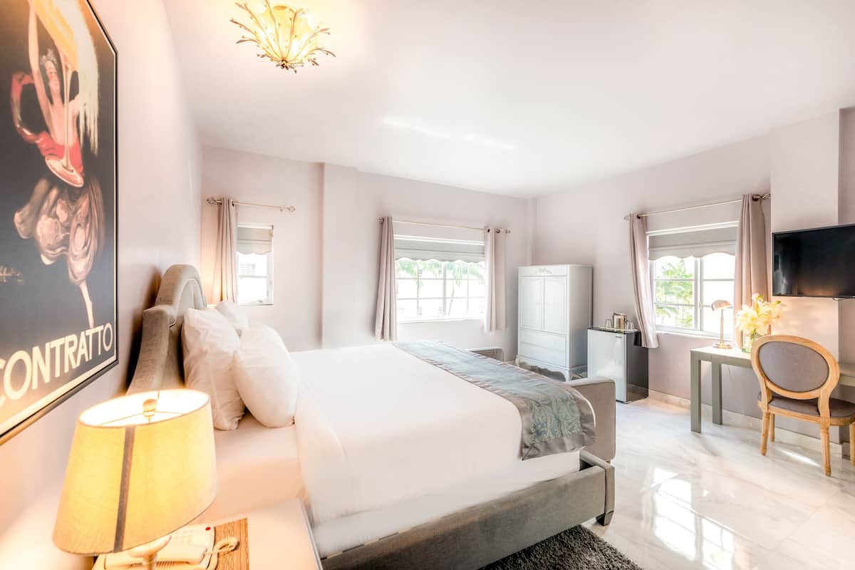 Een moderne hotelkamer met een groot bed, een bureau, een televisie en een kroonluchter.