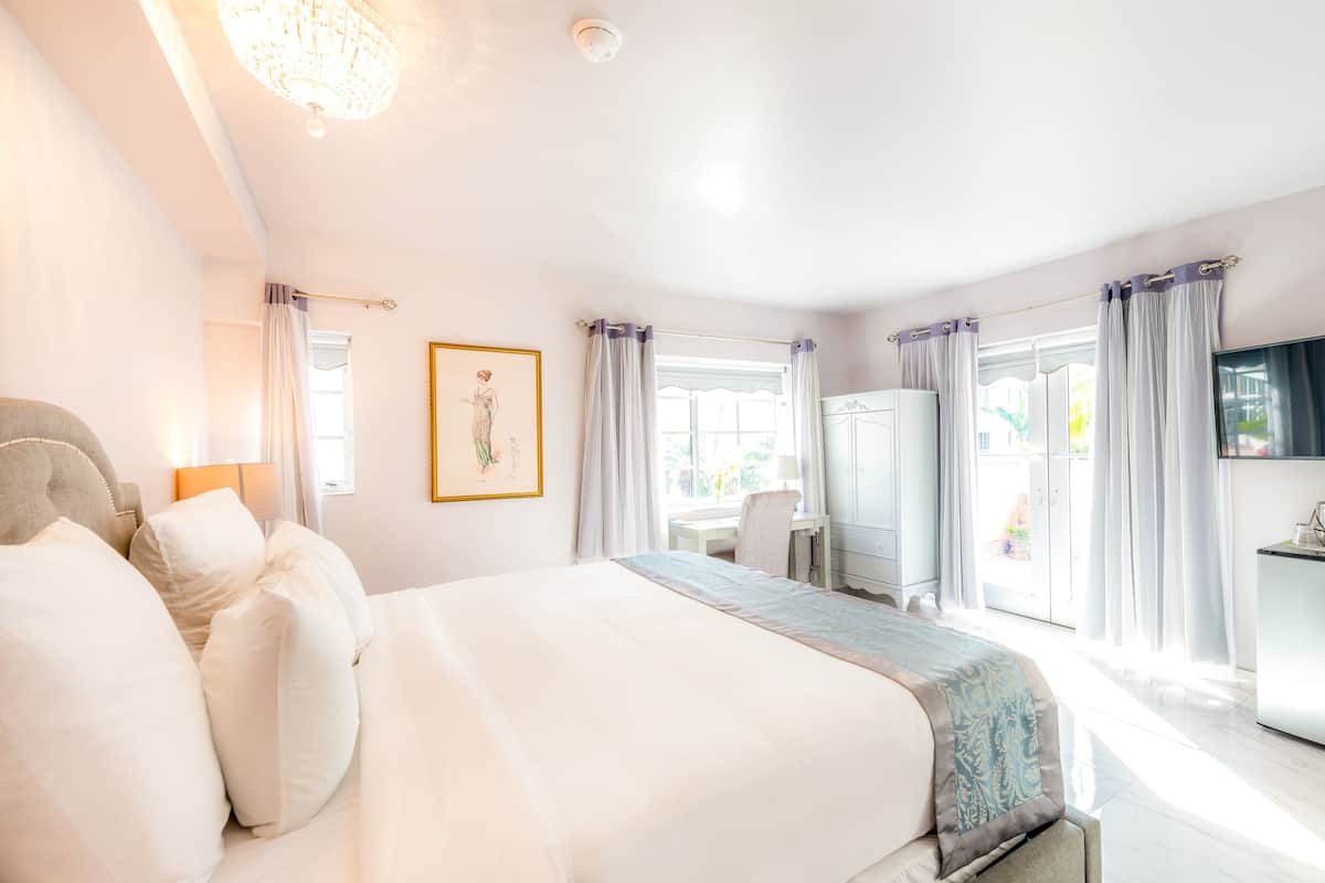 Een hotelkamer met een groot bed, een bureau, een stoel, een kledingkast en een televisie.