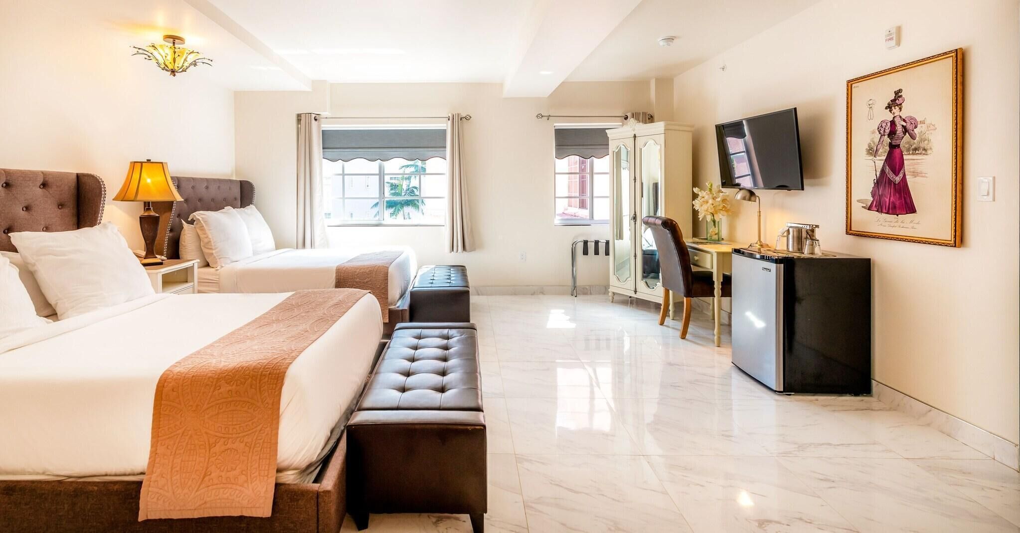 Une chambre d’hôtel avec un grand lit, un bureau, une télévision et un tableau au mur.