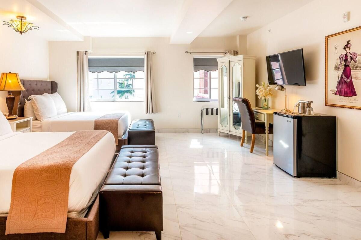 Een hotelkamer met een groot bed, een bureau, een televisie en een schilderij aan de muur.