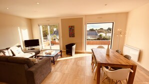 A modern living room with a sofa, TV, and dining area.