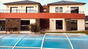 Un edificio moderno de dos pisos con una piscina delantera.