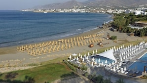 A resort with a large pool area, multiple sun loungers, and a beach with umbrellas. - Creta Sun Apartments (Ierapetra)