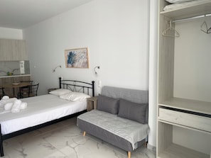 A bedroom with a bed, a sofa, a desk, and a wardrobe. - Creta Sun Apartments (Ierapetra)