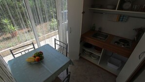 Una pequeña cocina con una mesa para dos comensales, un lavamanos y una ventana con vistas a un jardín.