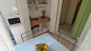 Una kitchenette compacta con microondas, lavamanos y estantes para guardar cosas.