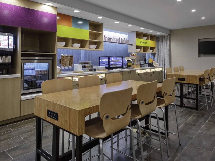 A modern restaurant with a long counter, multiple seating options, and a variety of food and drink stations.