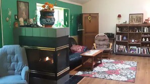 Una sala de estar con chimenea, un sofá, una silla, una estantería y suelo de madera.