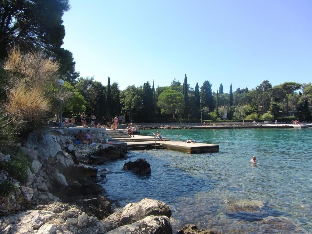 A coastal area with rocky shores, clear water, and people swimming and relaxing.