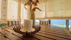 A wooden table with a white plate and a vase with dried flowers. - Charming retreat with panoramic private pool, 300m from the sea (Trinità d'Agultu e Vignola)