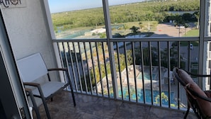 A balcony with a view of a swimming pool and a distant landscape. - Beach, Shelling, Water Sport, Restaurant Right Across The Street!  Paradise!! (Bonita Springs)