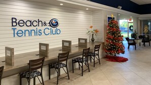 A reception area with a sign for 'Beach & Tennis Club', a Christmas tree, and several chairs and tables. - Beach, Shelling, Water Sport, Restaurant Right Across The Street!  Paradise!! (Bonita Springs)