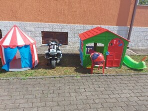 Kids can play in the tent and playhouse, with a toy motorcycle and car nearby.