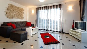 A modern living room with a sofa, coffee table, and a flat-screen TV. - Apartment Adria 1 on the island Krk (Malinska)