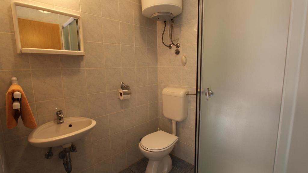 A bathroom with a sink, toilet, and a mirror.