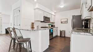 A modern kitchen with white cabinetry, stainless steel appliances, and a marble countertop. - Imogene Home — 4BR + Hot Tub, Sleeps 10, 15 min to Ski Cooper, Ping Pong Garage (Leadville)