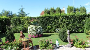 A well-maintained garden with various sculptures, a hedge, and a stone wall.