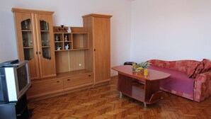 A living room with a wooden cabinet, a television, a sofa, and a coffee table.