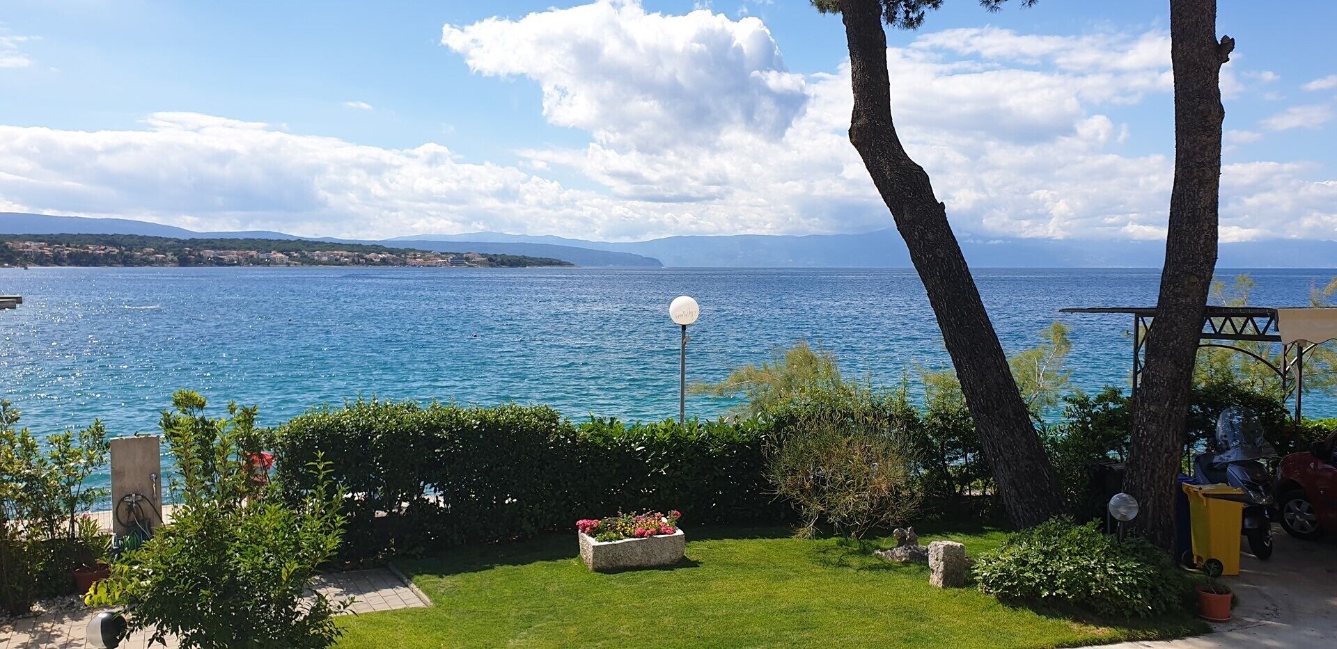 A coastal garden with a view of the sea, a lamp post, and a small seating area.