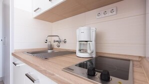 Uma cozinha moderna com fogão embutido, cafeteira e pia.
