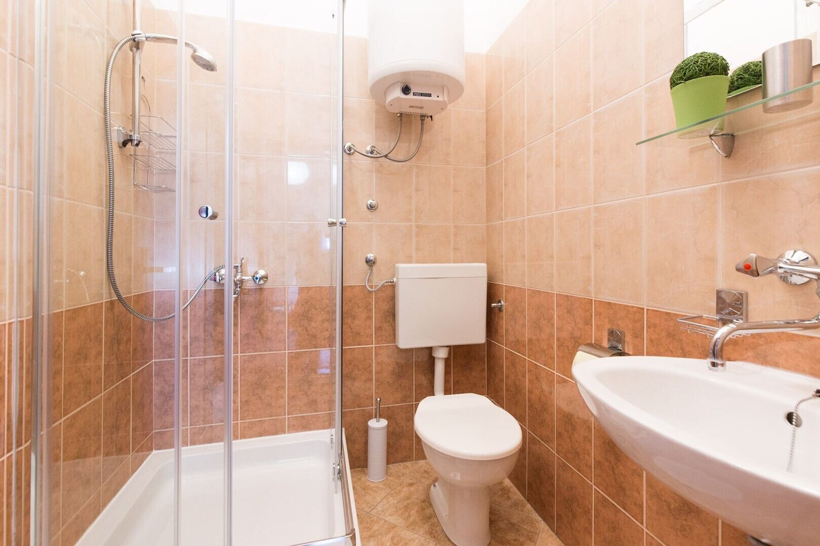 Een moderne badkamer met een douchecabine van glas, een toilet en een wastafel.